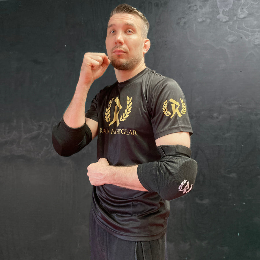 Rurik FG kyynärpääsuojat on suunniteltu erityisesti kamppailulajien harrastajille, jotka vaativat sekä mukavuutta että maksimaalista suojaa. Ne soveltuvat erinomaisesti Muay Thaihin, MMA:han ja muihin täyskontaktin lajeihin, joissa kyynärpäihin kohdistuu iskuja ja kontaktia. Kuvassa kyynärsuojat puettuna päälle. 