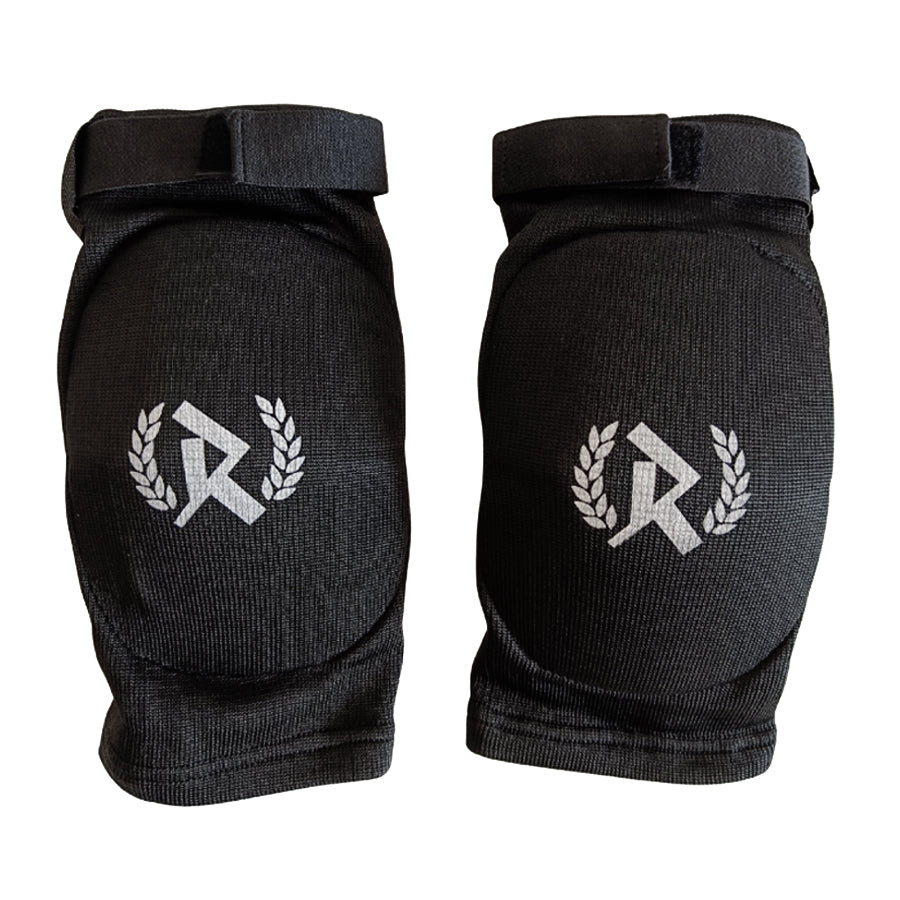 Rurik FG kyynärpääsuojat on suunniteltu erityisesti kamppailulajien harrastajille, jotka vaativat sekä mukavuutta että maksimaalista suojaa. Ne soveltuvat erinomaisesti Muay Thaihin, MMA:han ja muihin täyskontaktin lajeihin, joissa kyynärpäihin kohdistuu iskuja ja kontaktia. Kuvassa kyynärsuojat logo näkyvissä. 