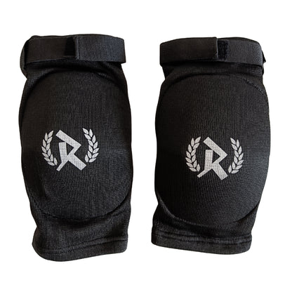 Rurik FG kyynärpääsuojat on suunniteltu erityisesti kamppailulajien harrastajille, jotka vaativat sekä mukavuutta että maksimaalista suojaa. Ne soveltuvat erinomaisesti Muay Thaihin, MMA:han ja muihin täyskontaktin lajeihin, joissa kyynärpäihin kohdistuu iskuja ja kontaktia. Kuvassa kyynärsuojat logo näkyvissä. 